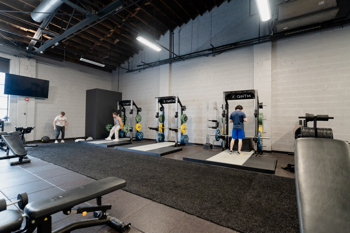 Squat racks on turf in the functional training area at QNTM Fit Life