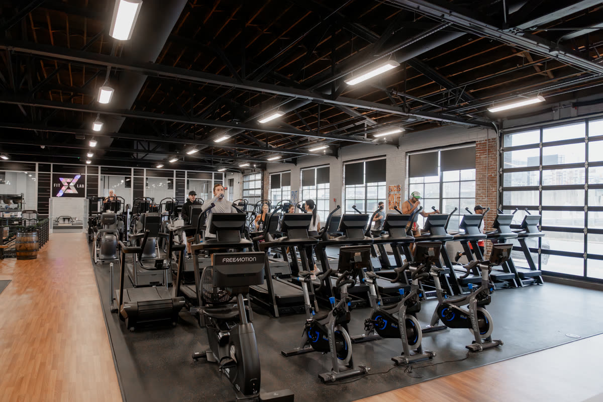 The cardio floor at QNTM Fit Life, rows of treadmills and bikes under the FitLab signage